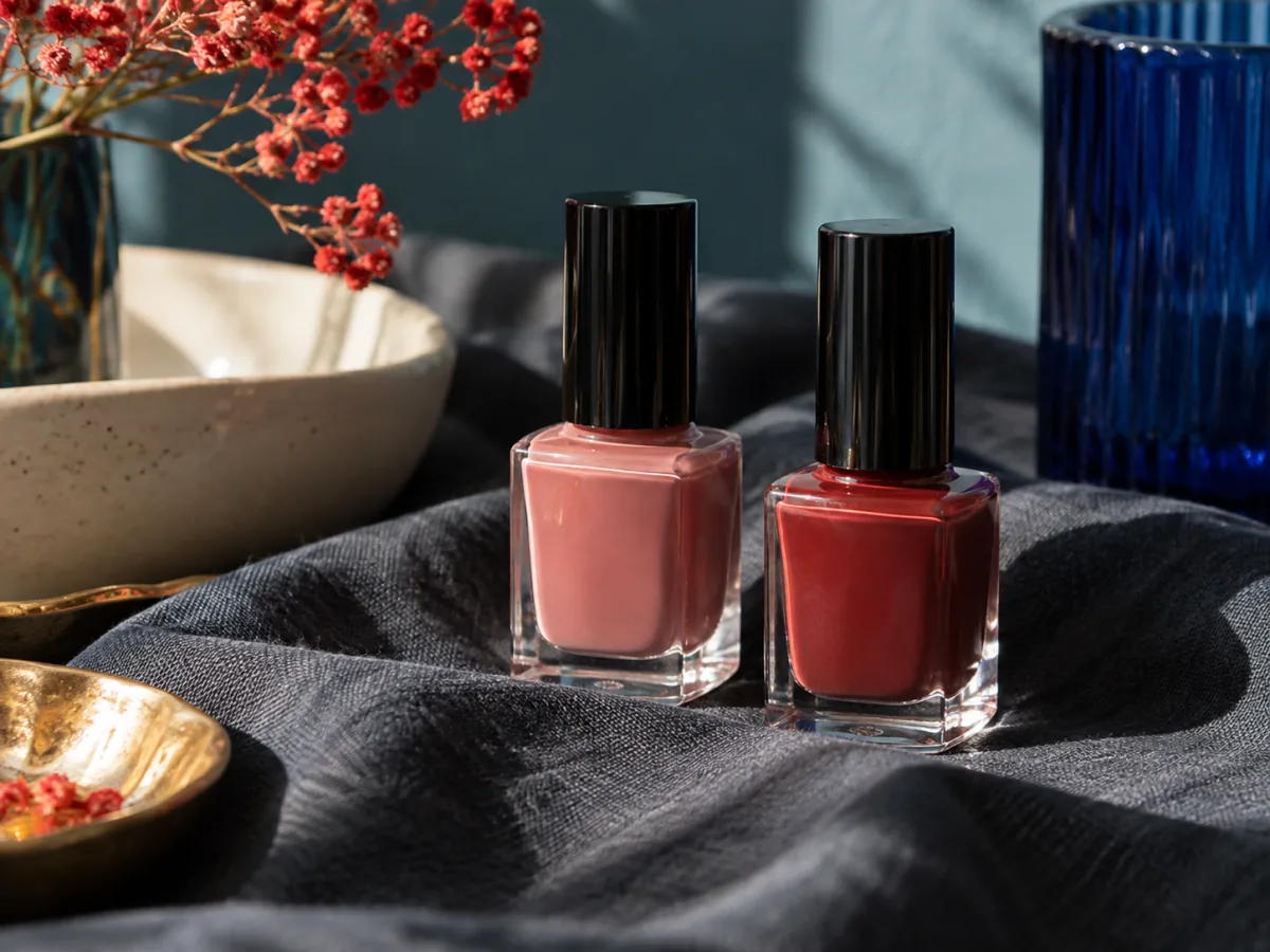 Red and rose polish bottles against a dark cloth